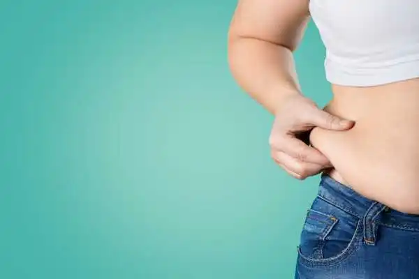 Image of woman pinching her love handles to show weight gain Stansted