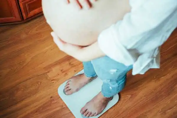 Image of woman weighing herself and experiencing weight gain through pregnancy Stansted